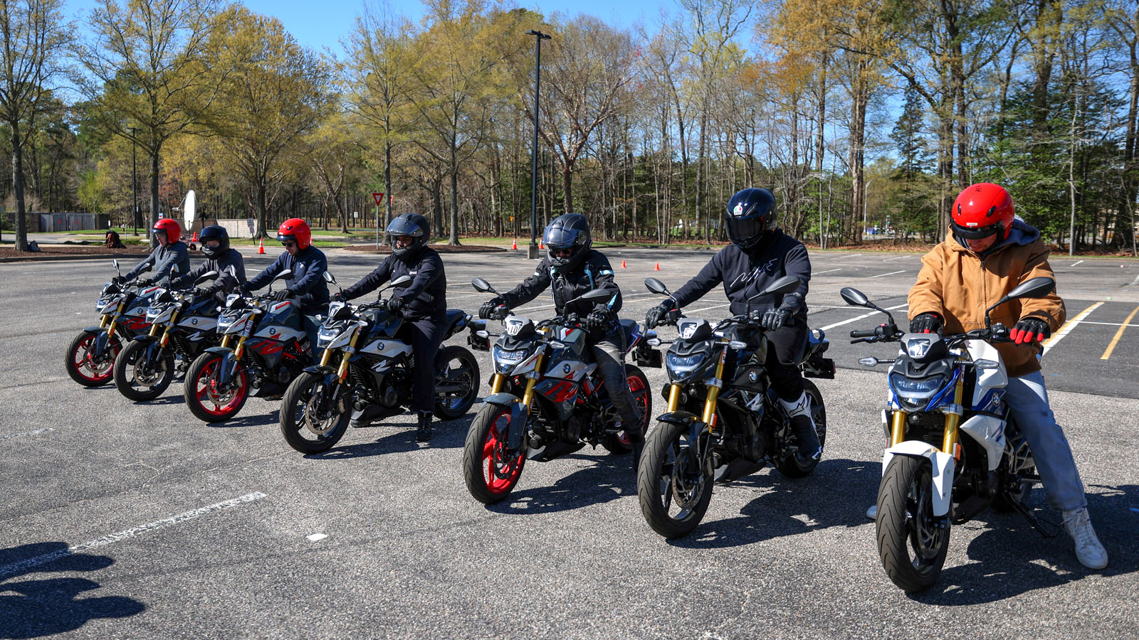 Seven motorcycle riders in a class on bikes lined up and wearing helmets