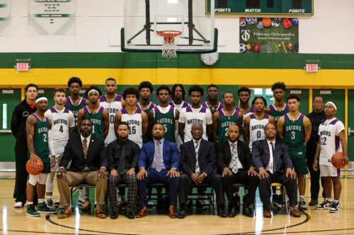 Basketball coach Chris Moore (sitting in navy suit) with the Men's Basketball team at high school