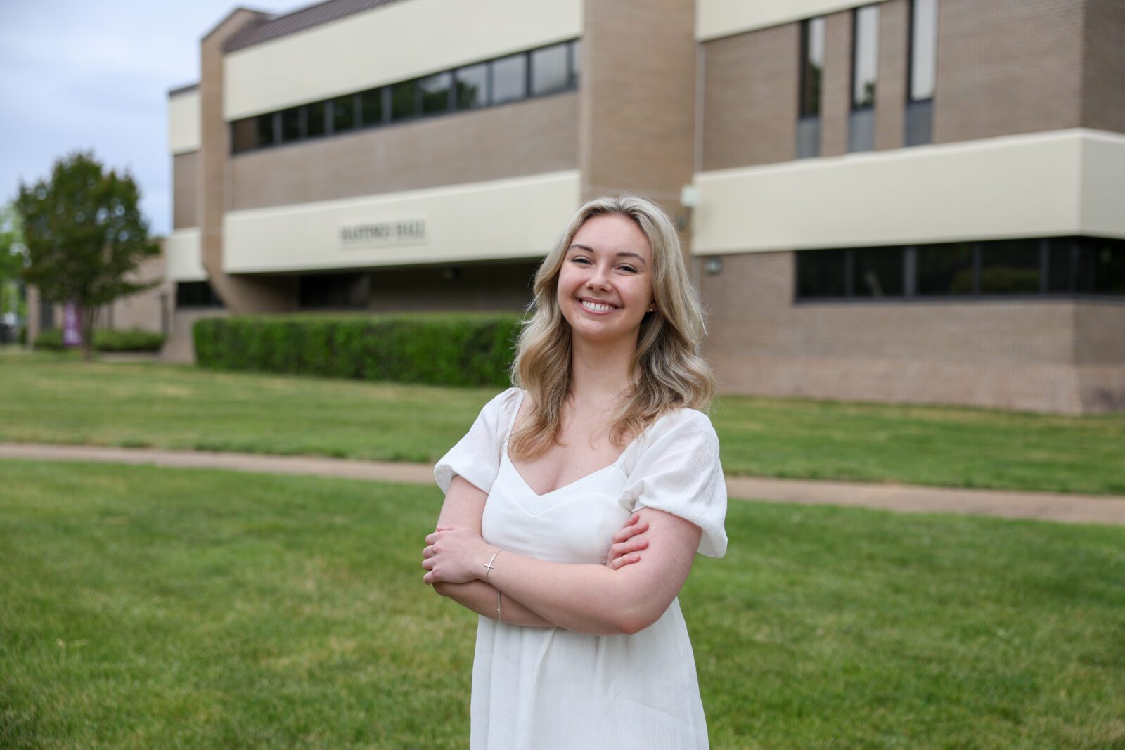 Emily Ballard, wearing a white outfit, standing near a Hampton Campus building